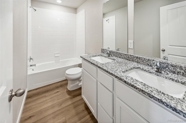 full bathroom featuring bathing tub / shower combination, wood-type flooring, double sink vanity, and toilet