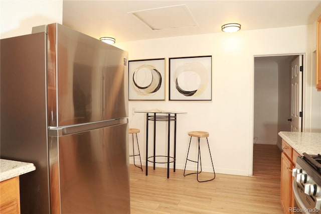 kitchen with light stone countertops, light hardwood / wood-style flooring, and stainless steel appliances