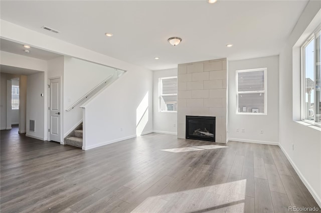 unfurnished living room with a tiled fireplace and hardwood / wood-style floors