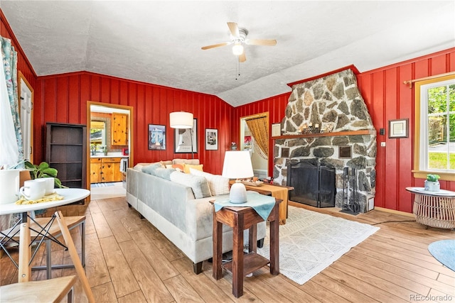 26351 Sheldon St, Kittredge, CO 80457 - living room featuring lofted ceiling, hardwood / wood-style flooring, ceiling fan, a textured ceiling, and a stone fireplace