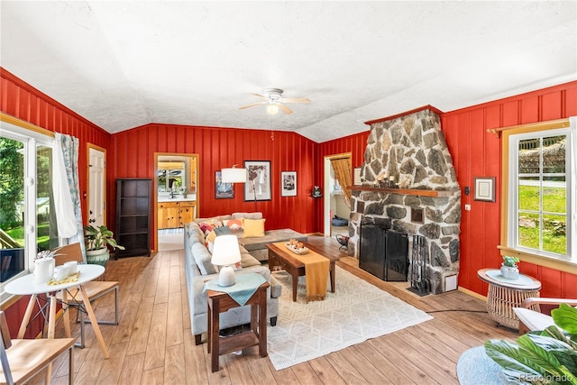 26351 Sheldon St, Kittredge, CO 80457 - living room featuring vaulted ceiling, hardwood / wood-style floors, a ceiling fan, a fireplace, and wooden walls