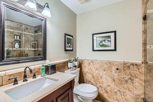 15373 Uravan St, Brighton, CO 80601 - full bathroom with tile walls, vanity, tiled shower, and wainscoting