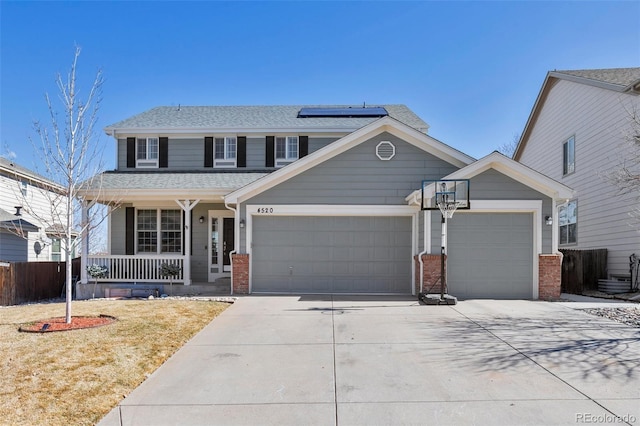 view of front of house featuring brick siding, a porch, an attached garage, roof mounted solar panels, and driveway