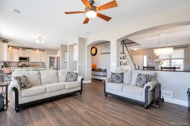 living room with baseboards, visible vents, arched walkways, stairway, and dark wood-style flooring