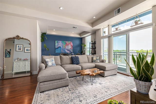 living room featuring recessed lighting, visible vents, baseboards, a tray ceiling, and dark wood finished floors