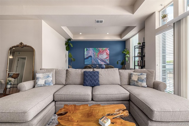 living area featuring a tray ceiling and visible vents