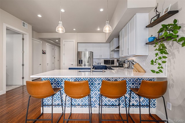 kitchen with a breakfast bar, pendant lighting, light countertops, and white cabinets