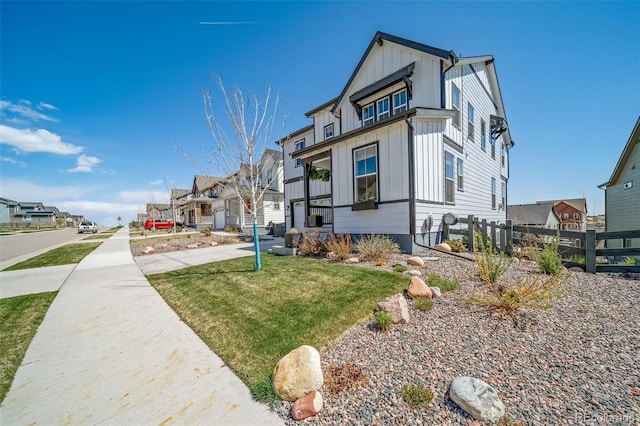 view of front of house with board and batten siding, fence, a front yard, and a residential view