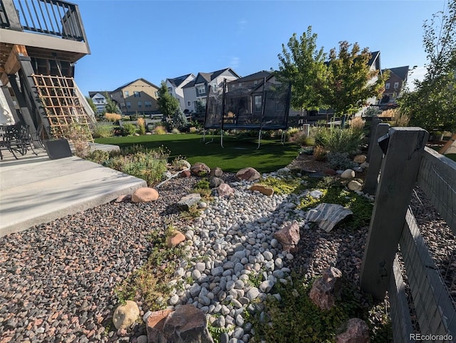 view of yard featuring fence, a residential view, a patio, and a trampoline