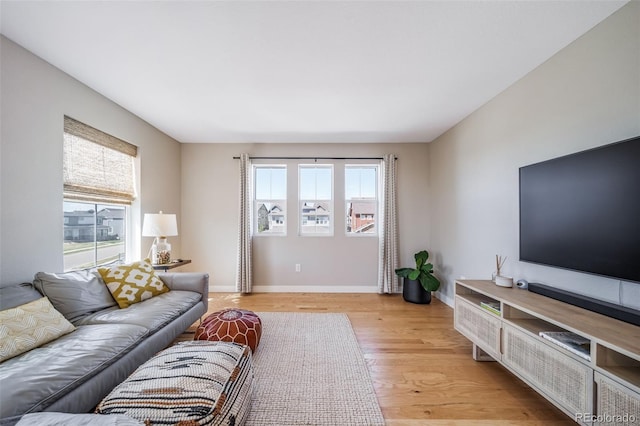 living room featuring plenty of natural light, light wood-style flooring, and baseboards