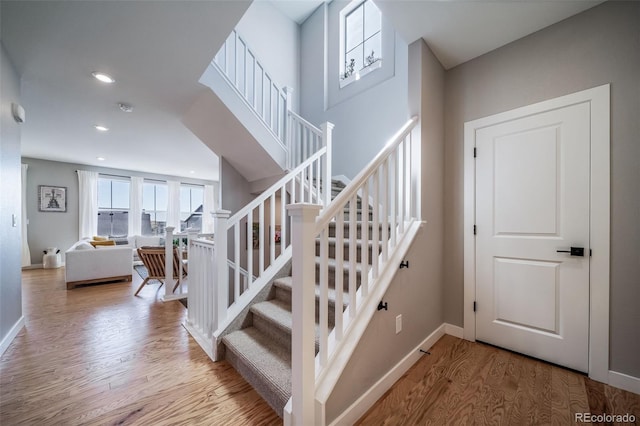 staircase featuring baseboards, wood finished floors, and recessed lighting