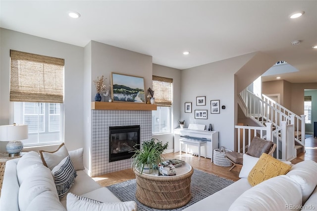living room featuring a tiled fireplace, recessed lighting, stairway, and a healthy amount of sunlight