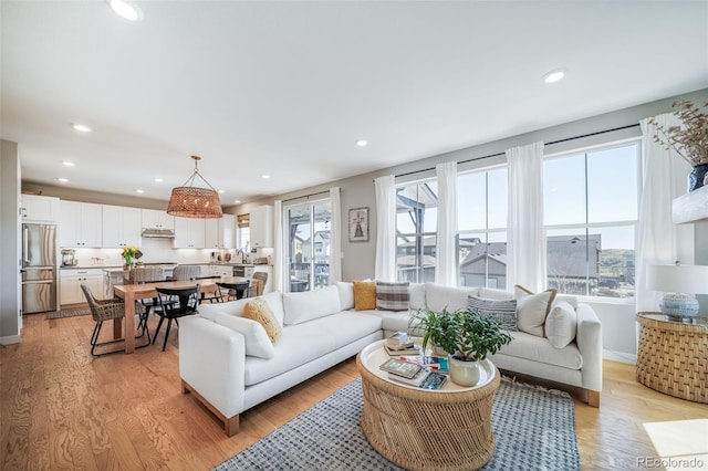 living area featuring baseboards, light wood-style flooring, and recessed lighting