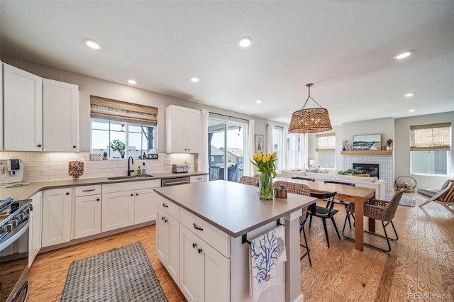 kitchen featuring open floor plan, stainless steel range with gas stovetop, a sink, and light wood-style flooring