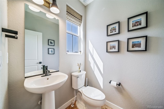 bathroom featuring wood finished floors, baseboards, a sink, and toilet
