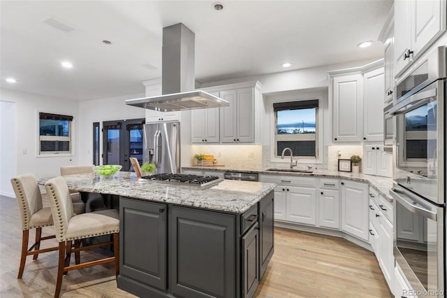 kitchen with a center island, stainless steel appliances, white cabinetry, sink, and island range hood