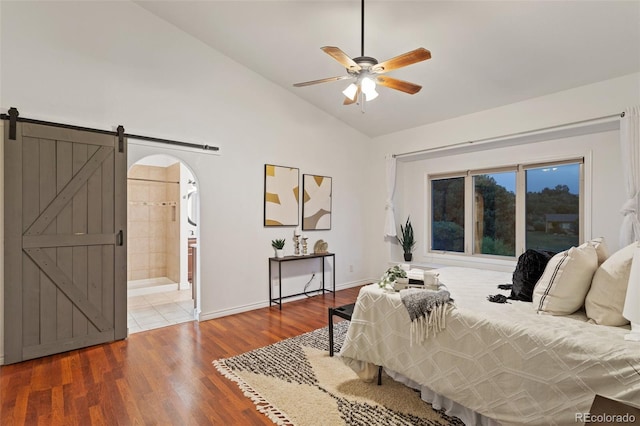 bedroom with ensuite bathroom, hardwood / wood-style flooring, lofted ceiling, a barn door, and ceiling fan