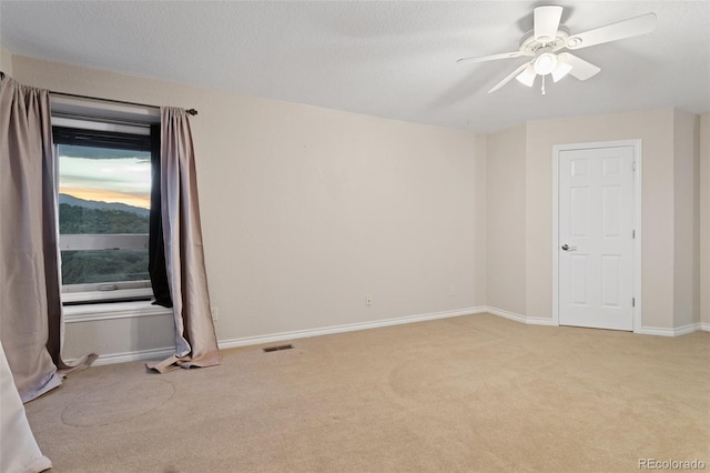 carpeted spare room with a textured ceiling and ceiling fan