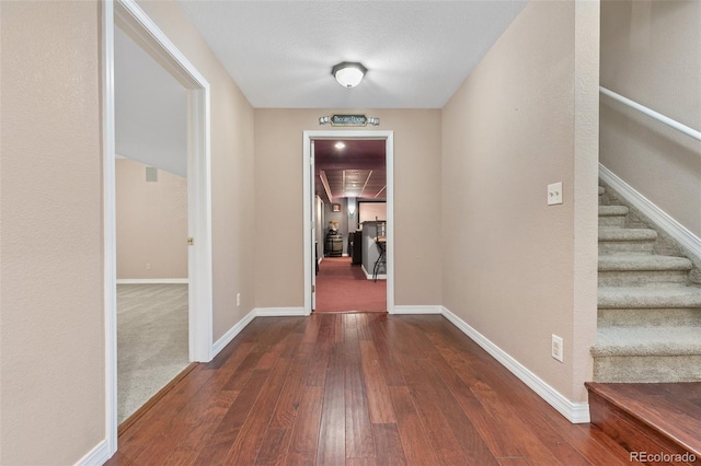 hallway with a textured ceiling and dark hardwood / wood-style floors