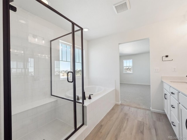 bathroom with wood-type flooring, vanity, and shower with separate bathtub