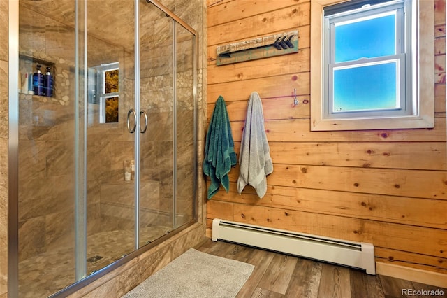 full bathroom with wood walls, a stall shower, wood finished floors, and a baseboard radiator