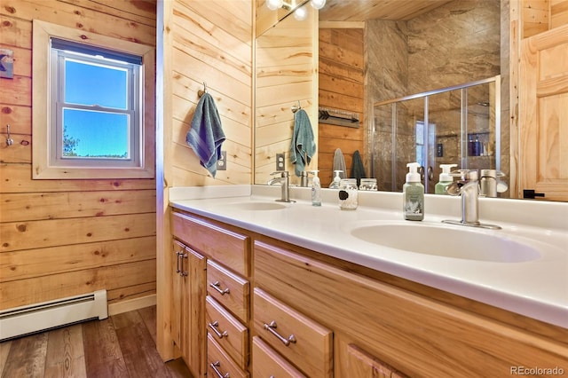 full bathroom featuring wood walls, a stall shower, a baseboard heating unit, and a sink