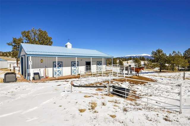 snow covered property featuring an outbuilding, an exterior structure, a chimney, and metal roof