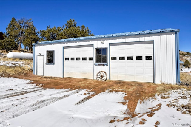 snow covered garage featuring a detached garage