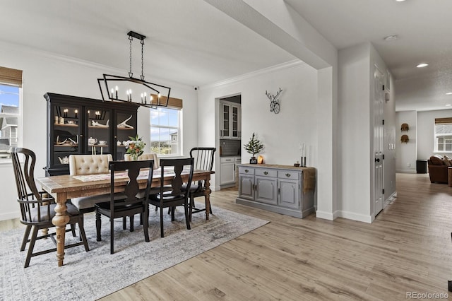 dining space with ornamental molding, a wealth of natural light, and light hardwood / wood-style floors