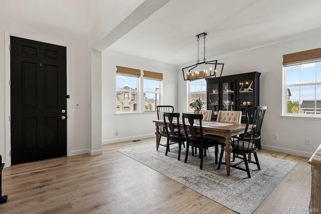 dining room featuring an inviting chandelier, ornamental molding, and light hardwood / wood-style floors