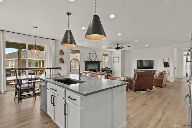 kitchen with sink, white cabinetry, stainless steel dishwasher, an island with sink, and pendant lighting