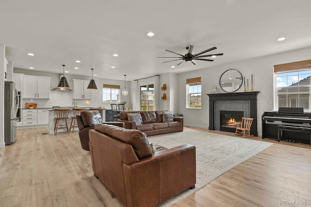 living room featuring ceiling fan, plenty of natural light, and light hardwood / wood-style flooring