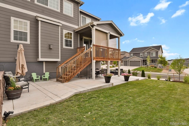 rear view of house with a wooden deck, a patio area, and a lawn