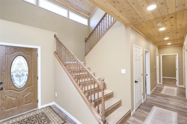 foyer entrance with recessed lighting, a towering ceiling, wood finished floors, wooden ceiling, and baseboards