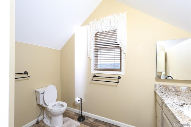 half bathroom featuring lofted ceiling, baseboards, toilet, and vanity