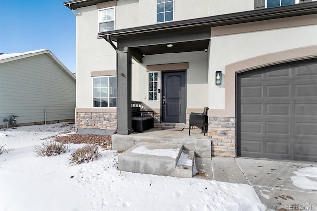 snow covered property entrance with a garage