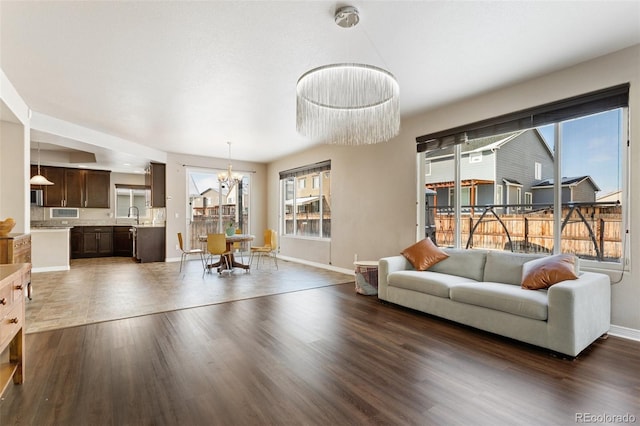 living room featuring sink, a wealth of natural light, dark hardwood / wood-style flooring, and a chandelier