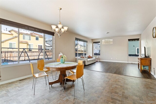 dining space with plenty of natural light, wood-type flooring, and a notable chandelier