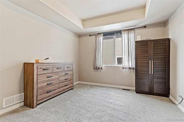 carpeted bedroom with a raised ceiling