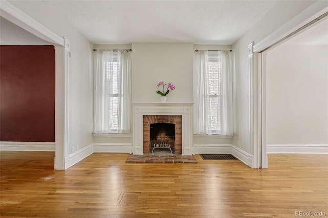 351 Bannock St, Denver, CO 80223 - unfurnished living room featuring a fireplace, a textured ceiling, wood finished floors, and healthy amount of natural light