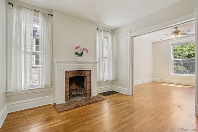 351 Bannock St, Denver, CO 80223 - unfurnished living room featuring light wood-type flooring, a brick fireplace, and ceiling fan