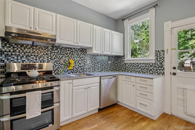 351 Bannock St, Denver, CO 80223 - kitchen with appliances with stainless steel finishes, under cabinet range hood, white cabinets, healthy amount of natural light, and a textured ceiling