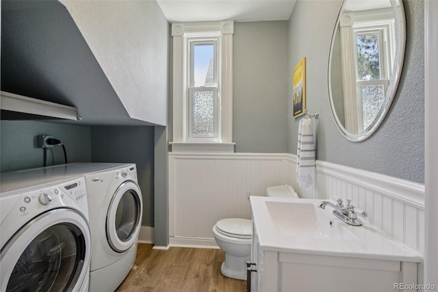 351 Bannock St, Denver, CO 80223 - laundry area with washing machine and clothes dryer, a wainscoted wall, and light wood-type flooring