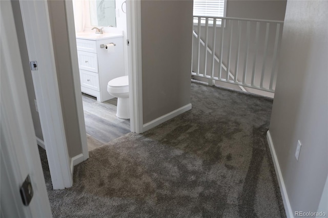 hallway featuring dark colored carpet and sink