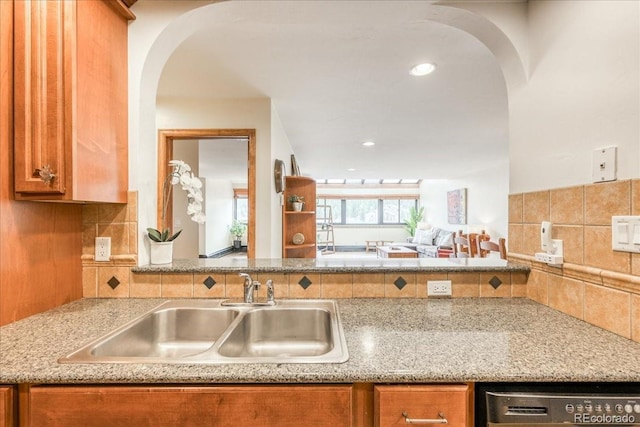 189 Ten Mile Cir Unit 551, Frisco, CO 80443 - kitchen with a sink, arched walkways, dishwasher, brown cabinetry, and decorative backsplash