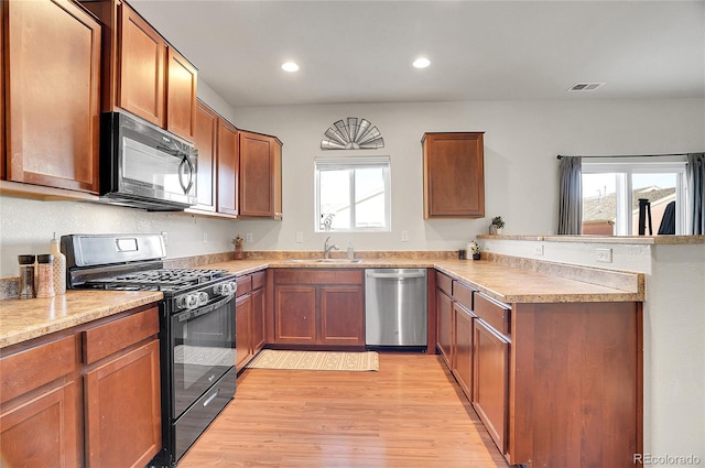 kitchen with sink, light hardwood / wood-style flooring, black appliances, and kitchen peninsula