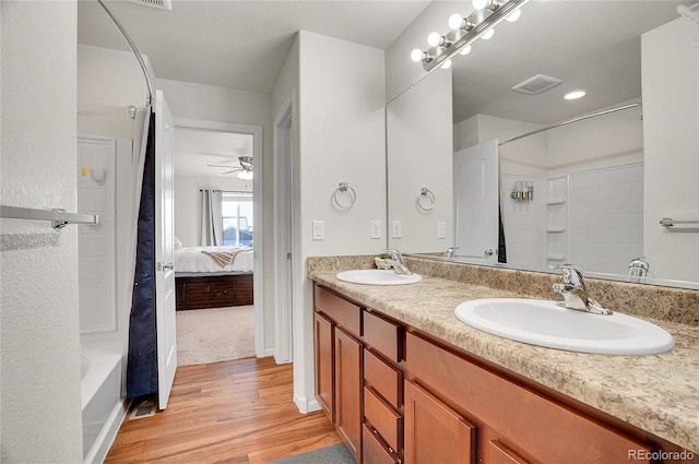 bathroom with hardwood / wood-style flooring, ceiling fan, vanity, and bathing tub / shower combination