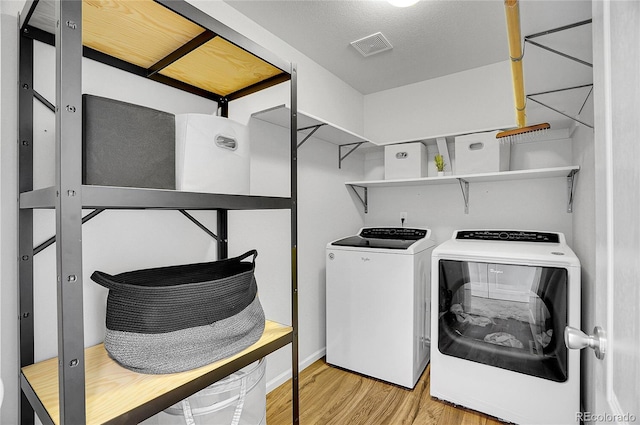 clothes washing area featuring separate washer and dryer and light hardwood / wood-style floors