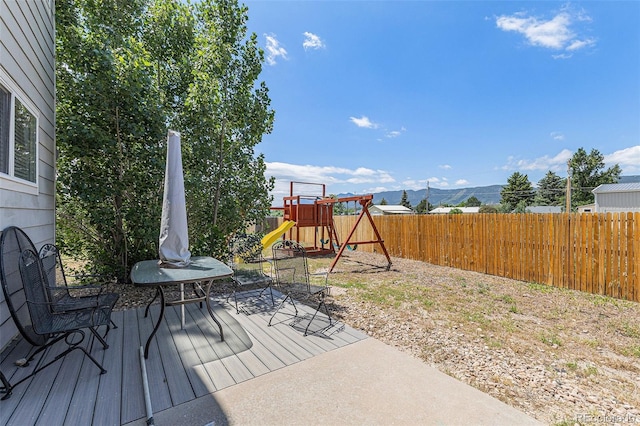 17464 Crestview Ct, Monument, CO 80132 - wooden terrace featuring a playground, a fenced backyard, and a mountain view