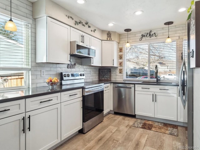 kitchen featuring dark countertops, light wood-type flooring, white cabinets, and stainless steel appliances